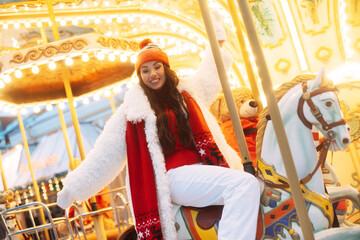 Laughing young woman at the winter fair riding a horse, carousel, Christmas carelessness and fun.