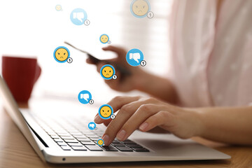 Social media dislike reaction. Woman using laptop and mobile phone at table, closeup. Thumbs down...