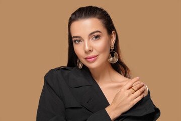 Portrait of young woman with beautiful makeup on light brown background