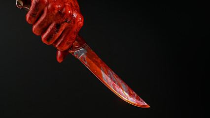 A man with bloody hands brandishes a knife on a black background.  © Михаил Решетников