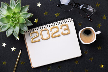 New year resolutions 2023 on desk. 2023 resolutions list with notebook, coffee cup on black background. Goals, resolutions, plan, action, checklist concept. New Year 2023 template, copy space