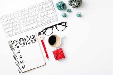 New year resolutions 2023 on desk. 2023 resolutions list with notebook, coffee cup, decorations on white background. Goals, resolutions, plan, action, checklist concept. New Year 2023 template