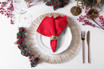Plates with red fabric napkin, cutlery and festive decor on white table, flat lay