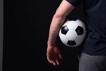 Athletic man with soccer ball on black background, closeup. Space for text