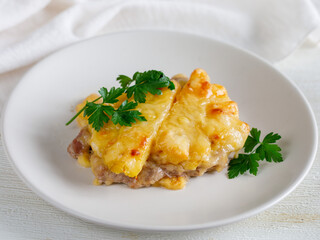 Baked Pork Steak with Pineapple grated with cheese on white plate close up.