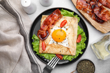 Delicious crepe with egg served on light gray table, flat lay. Breton galette
