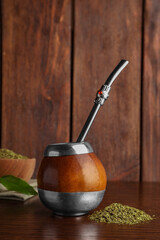 Calabash with mate tea and bombilla on wooden table