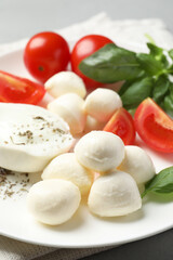 Delicious mozzarella with tomatoes and basil leaves on table, closeup