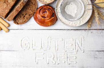 Many different products and phrase Gluten free written with flour on white wooden table, flat lay