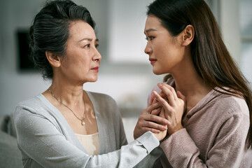young asian daughter comforting elderly mother