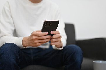 cropped image, A young man using his smartphone on sofa in the living room.