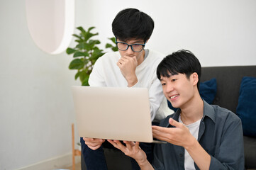 Two of smart young Asian male college students doing school project together