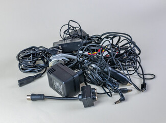 Bunch of old wires, connections and chargers for modern devices close-up on a light background....