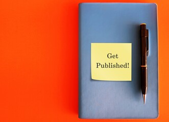 Blue notebook and pen, with text typed note GET PUBLISHED, concept of first time being a book writer or author , and must get it published to sell to public