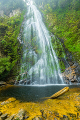 a tall waterfall falling through the jungle to a pool below near Sapa in Vietnam.