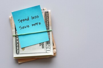 Dollars cash money on copy space background with handwritten text note SPEND LESS SAVE MORE,...
