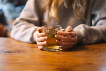 Portrait of a joyful teengirl enjoying a cup of tea at cafe. Smiling beautiful girl drinks hot tea in winter. Teengirl drinking hot tea. Cafe city lifestyle. Colorful portrait of happy pretty girl