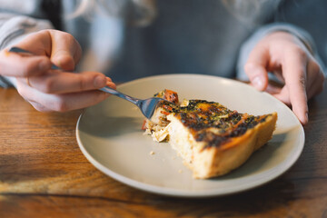 Young teengirl eating quiche with fresh vegetable and breakfast of wellness lifestyle at cafe. French quiche. Homemade tart.