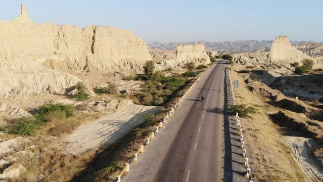 Aerial View Over Along Empty Highway Road Through Hingol National Park In Balochistan Desert Landscape With Motorbike Going Past