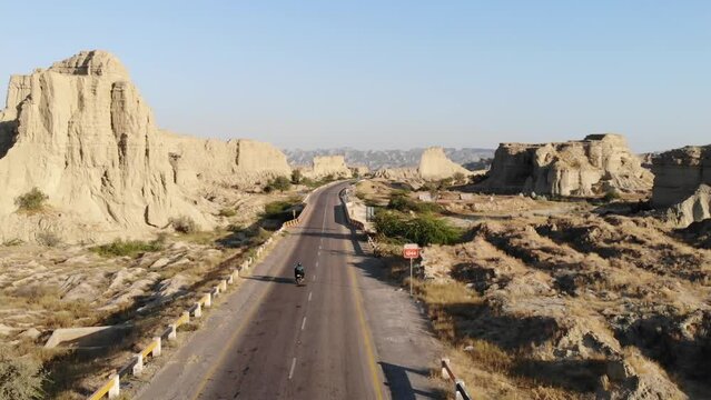 Aerial Tracking Shot Behind Motorbike Driving Along Empty Highway Road Through Hingol National Park In Balochistan Desert Landscape.