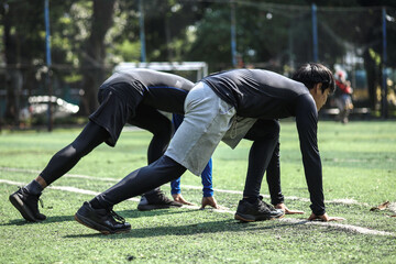 Obraz premium Side view of two young man in starting position for running at the court.