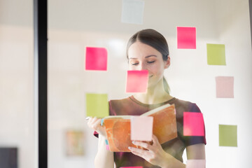 Business woman meeting at office and use post it notes in glass wall  to share idea. Brainstorming business office concept. Sticky note on glass wall.