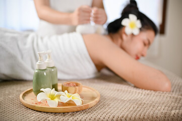 Obraz na płótnie Canvas selective focus, Massage oil bottles, body scrub and frangipani flowers on massage table
