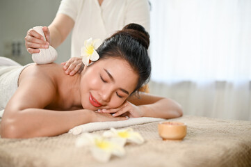 Plakat Happy Asian woman lying on spa table with eyes closed, receiving Thai body massage