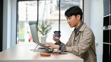 Handsome Asian male programmer or freelance graphic designer remote working at the coffee shop