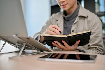 Smart Asian male programmer or web developer concentrating on his task, taking notes