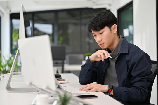Asian male programmer working at his office desk. Young male officer working on his task.