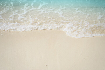 Fototapeta na wymiar Sand beach seashore with blue wave and white foamy from blue sea in summer.