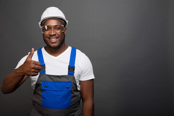 Smiling black worker in helmet and goggles with a gesture of admiration close-up. An African...