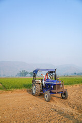 Obraz premium Indian farmer working with tractor in agriculture field.