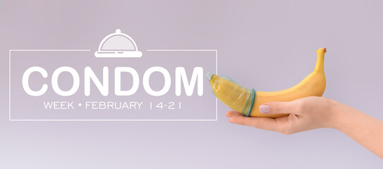 Female hand with banana in condom on grey background. National Condom Week