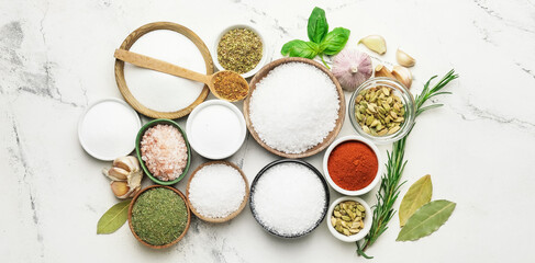 Bowls with different spices and herbs on light background