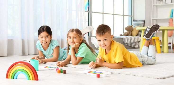 Little children painting rainbow in kindergarten
