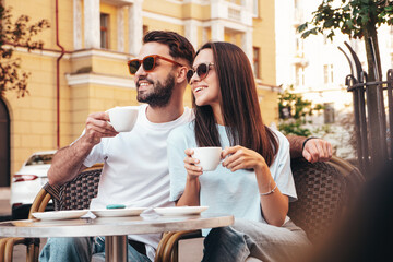 Smiling beautiful woman and her handsome boyfriend. Happy cheerful family. Couple drinking coffee in restaurant. They drinking tea at cafe in the street. Holding cup. Enjoying their date