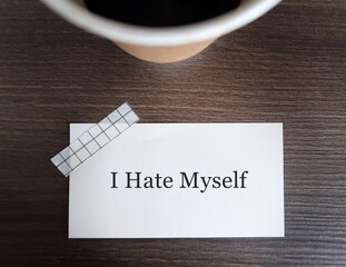 Coffee cup on wood background with text note I HATE MYSELF , concept of self-talk with self-hatred...