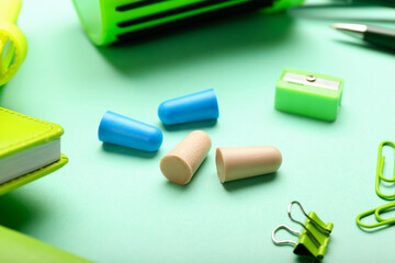 Different earplugs and stationery on color background