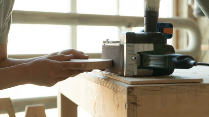 hands of a carpenter girl grind a wooden blank on a grinder
