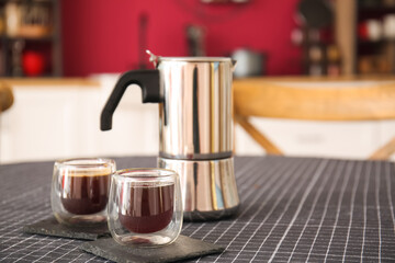 Coffee pot and cups on dining table in stylish kitchen