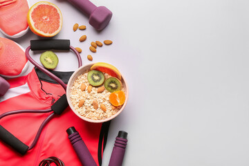 Sports clothes, shoes, equipment and bowl with healthy food on light background