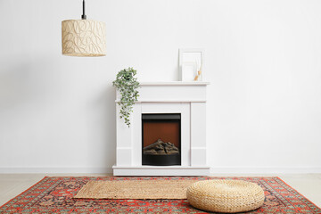 Interior of room with wicker pouf and fireplace near white wall - obrazy, fototapety, plakaty