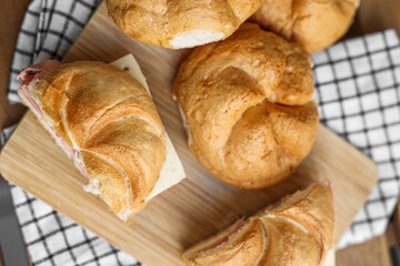Delicious kaiser rolls with ham and cheese on table
