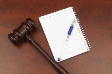 Blank note pad with pen and judge gavel on wooden table. Creating new laws concept.