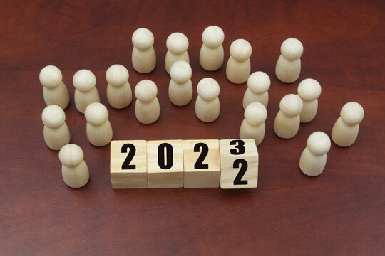 Many wooden people figures and cubes with flipping numbers 2022 and 2023. People in year 2023 concept.