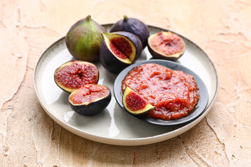 Plate with ripe figs and puree on color background