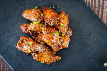 fried chicken with garlic and sesame in caramel on a black tray.