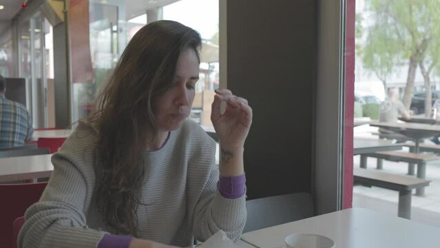 Mujer comiendo hamburguesa en restaurante comida r&aacute;pida (Formato LOG para edici&oacute;n y correcci&oacute;n de color profesional)	